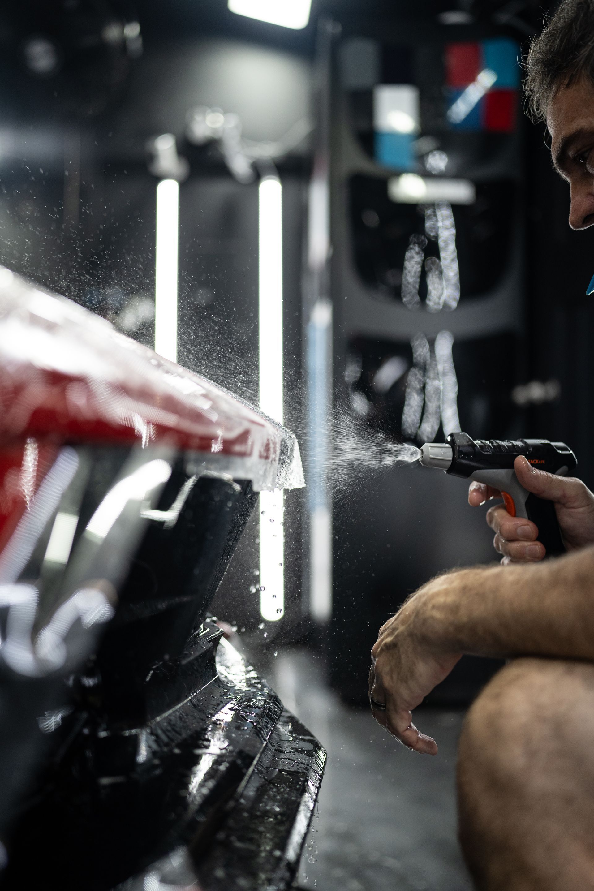 A man is spraying water on a car in a garage.