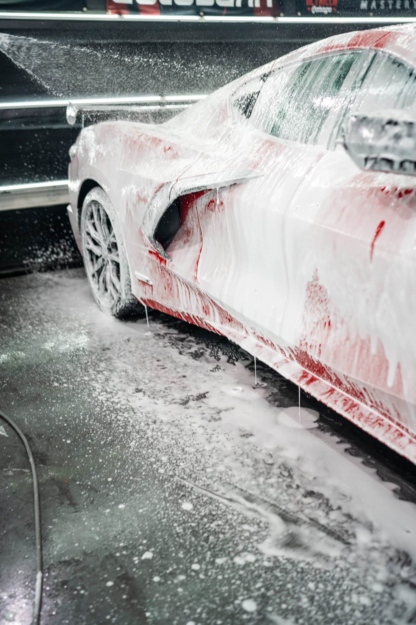 A car is covered in foam while being washed at a car wash.