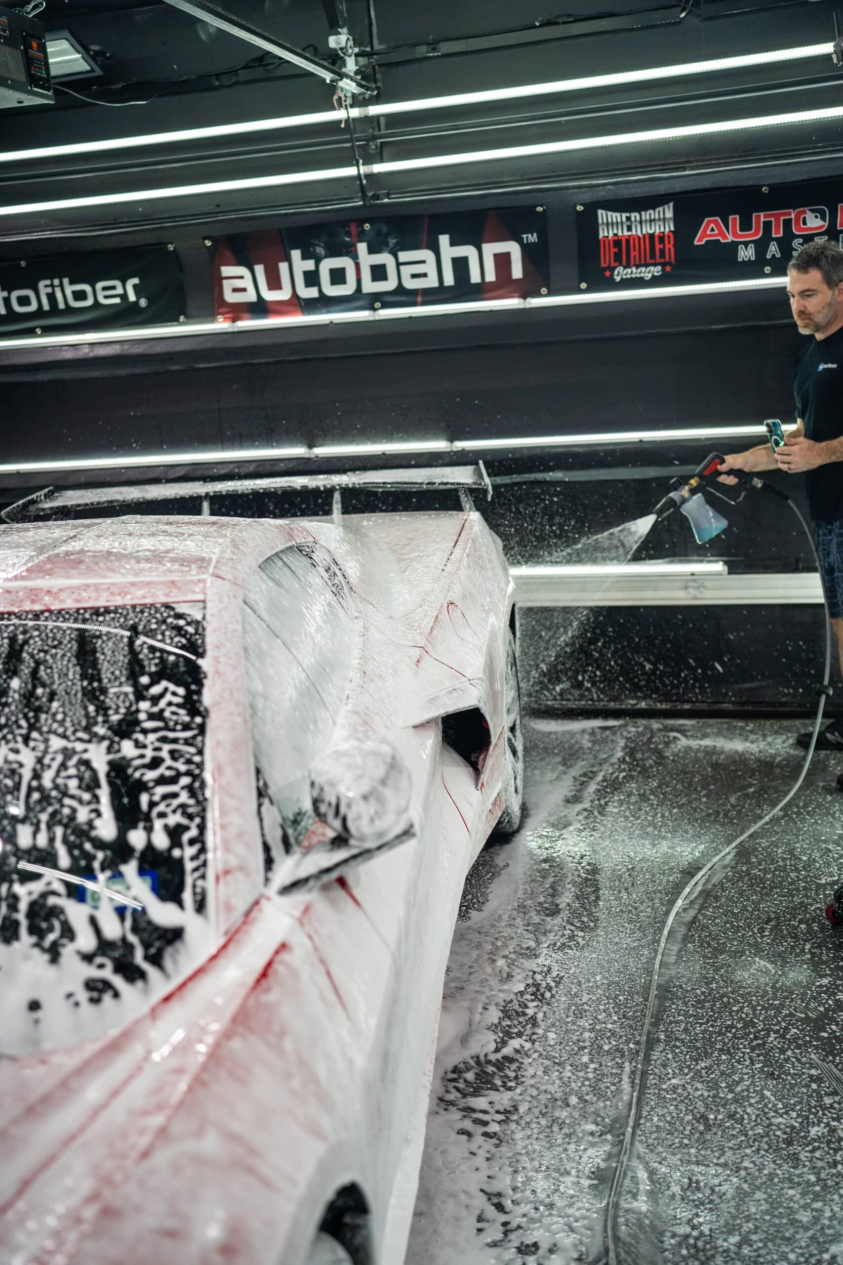 A man is washing a car with foam in a car wash.