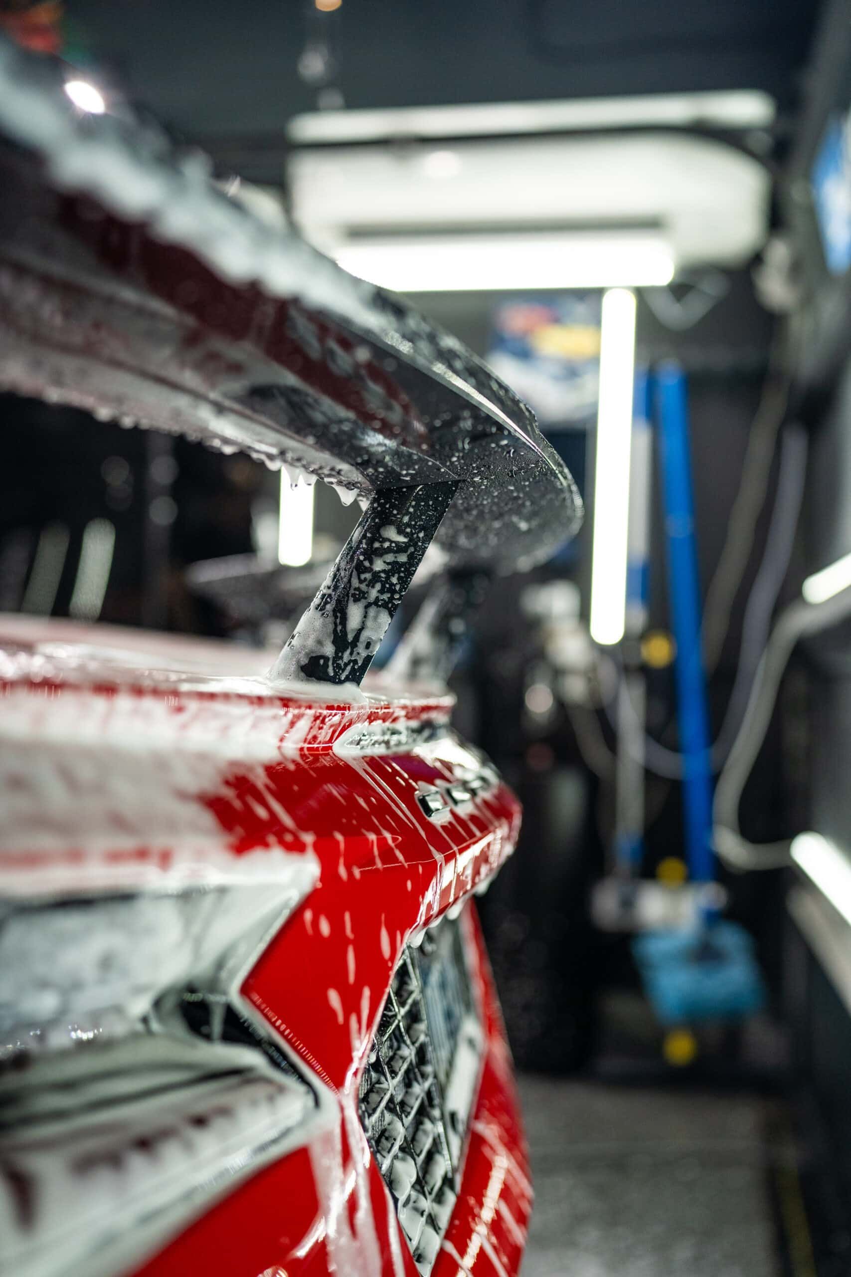A close up of a red car being washed in a car wash.
