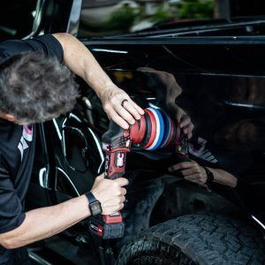 A man is polishing a car with a machine.