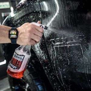 A person is spraying a car with a spray bottle.