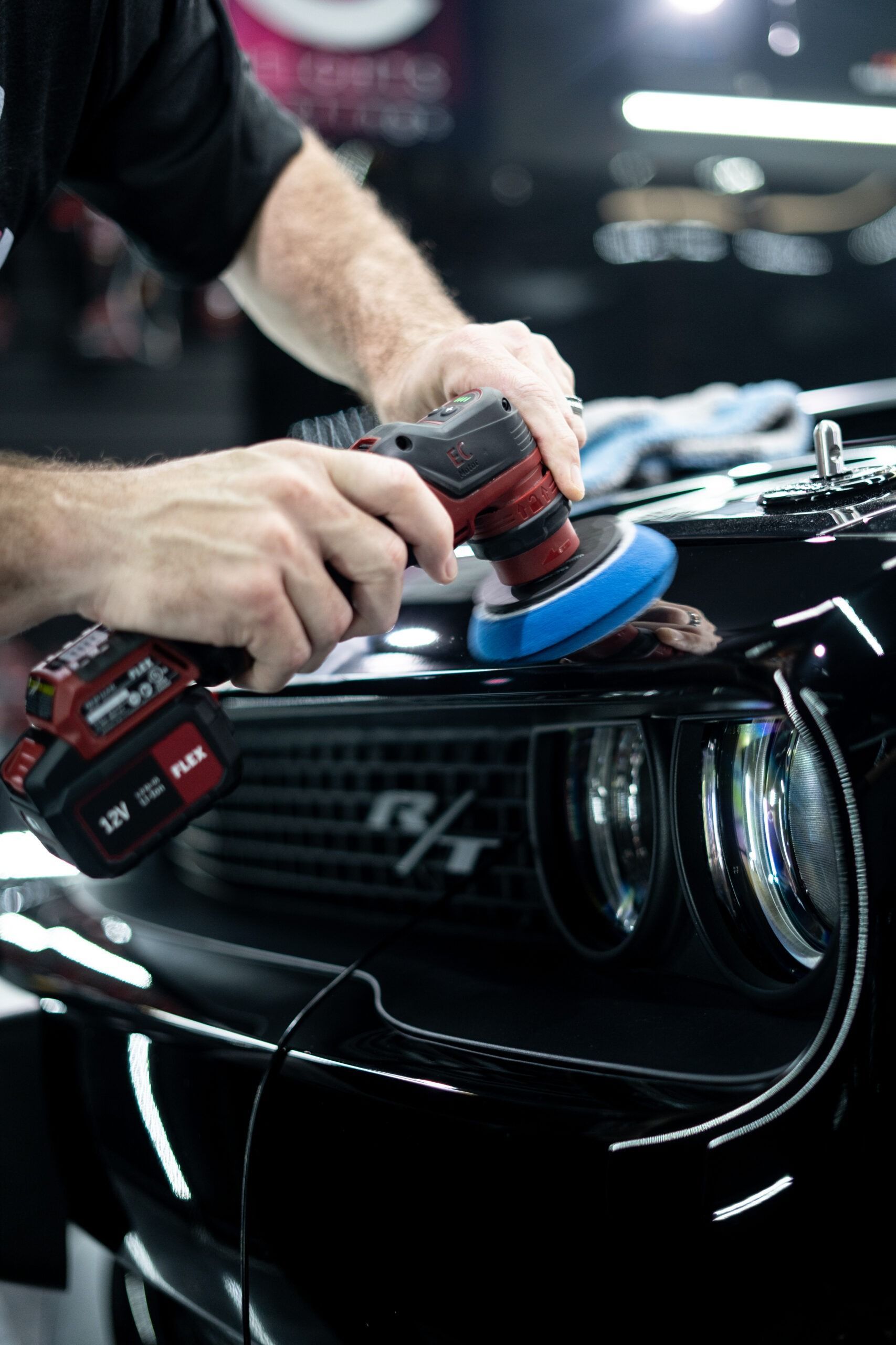 A man is polishing a black car with a machine.