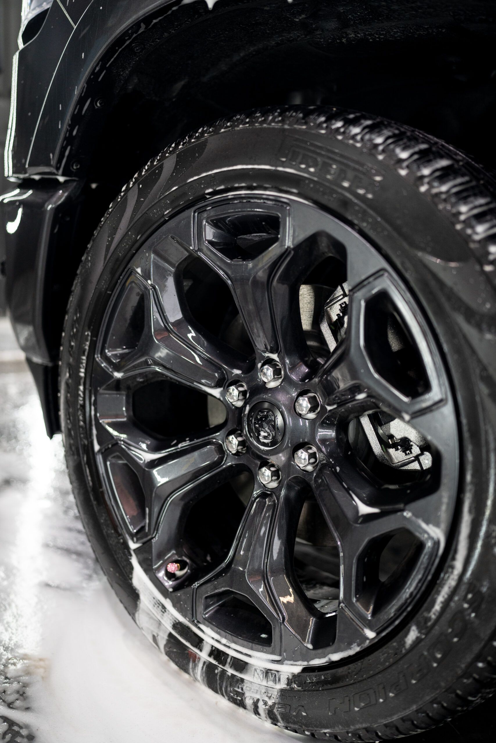 A close up of a black car wheel with soap on it.