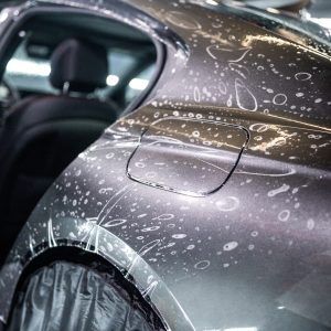 A close up of a car covered in plastic wrap.