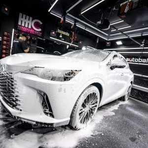 A white car is covered in foam in a garage.