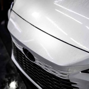 A close up of the front of a white car with a black grill.