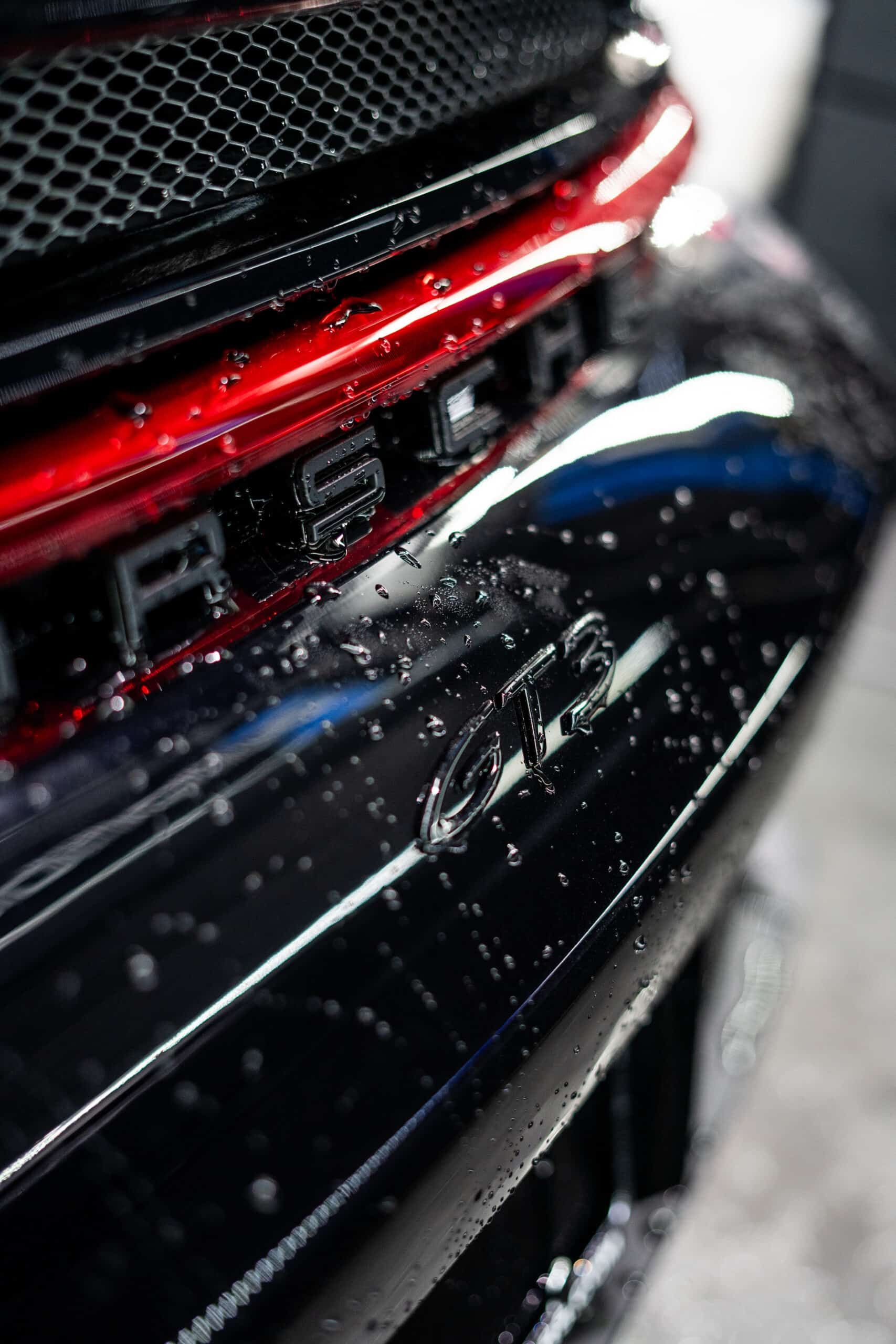 A close up of a black car with water drops on it.
