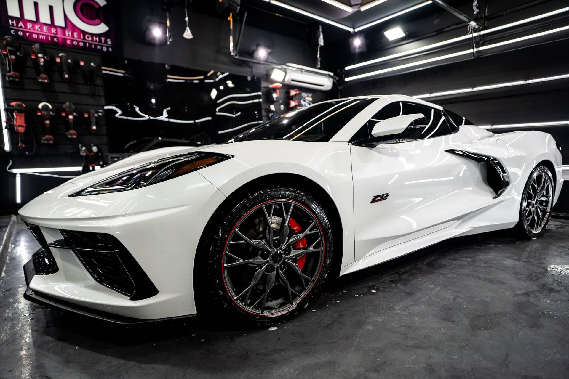A white sports car is parked in a garage.