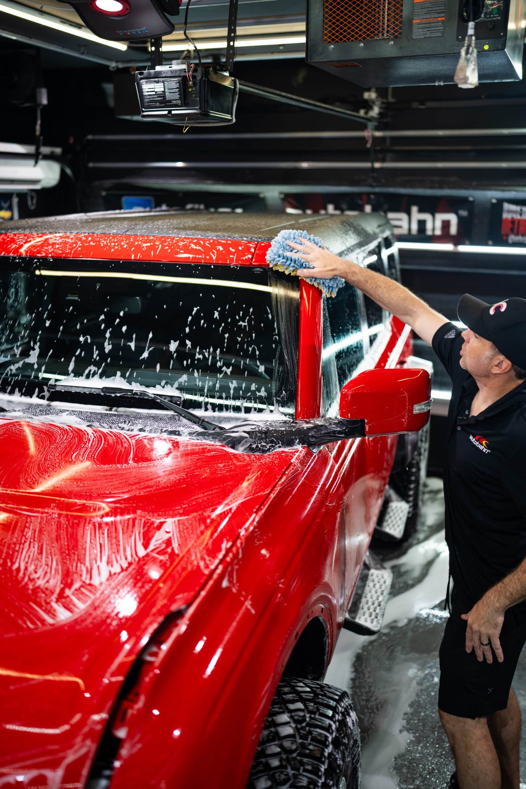 A man is washing a red truck in a garage.