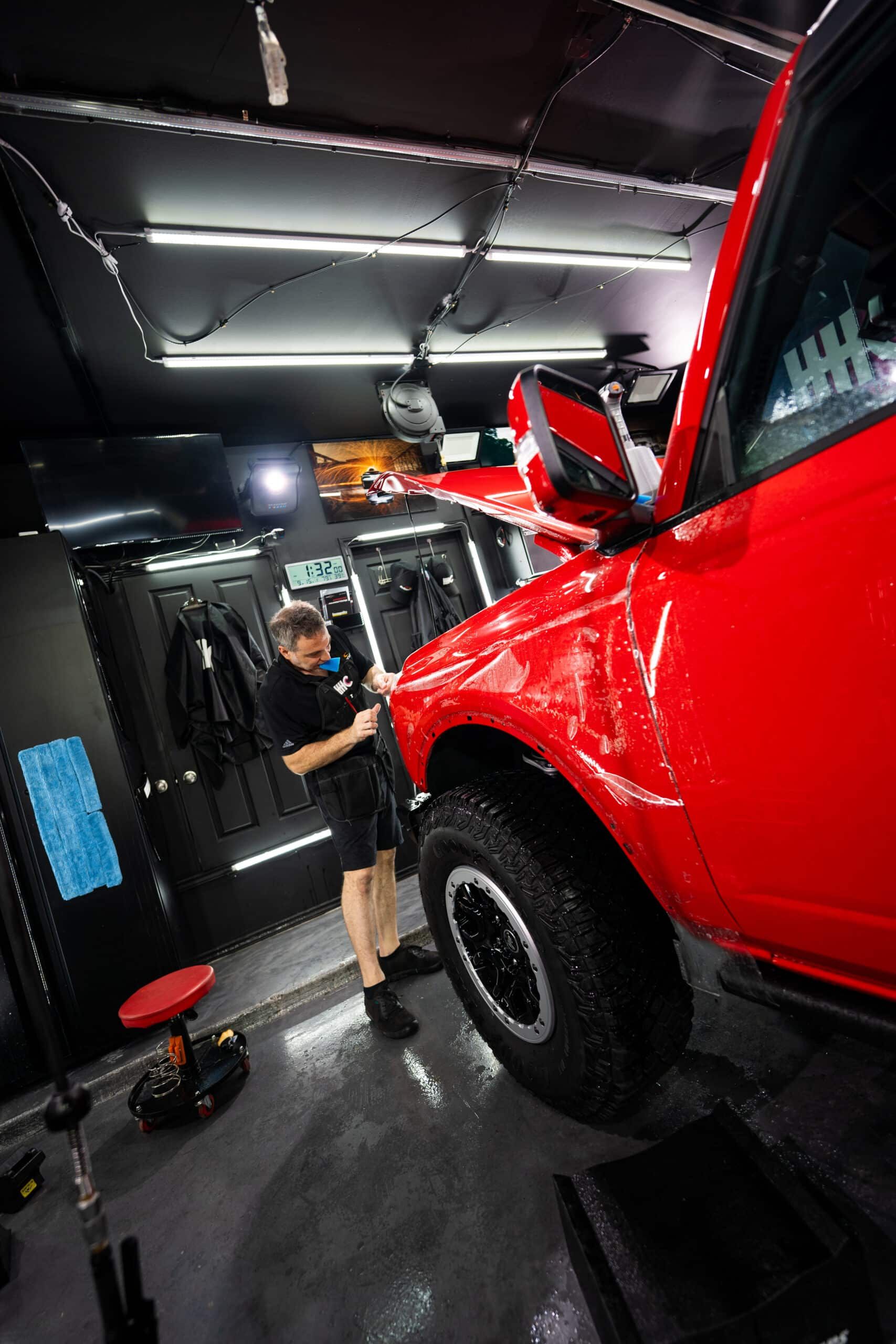 A man is standing next to a red truck in a garage.