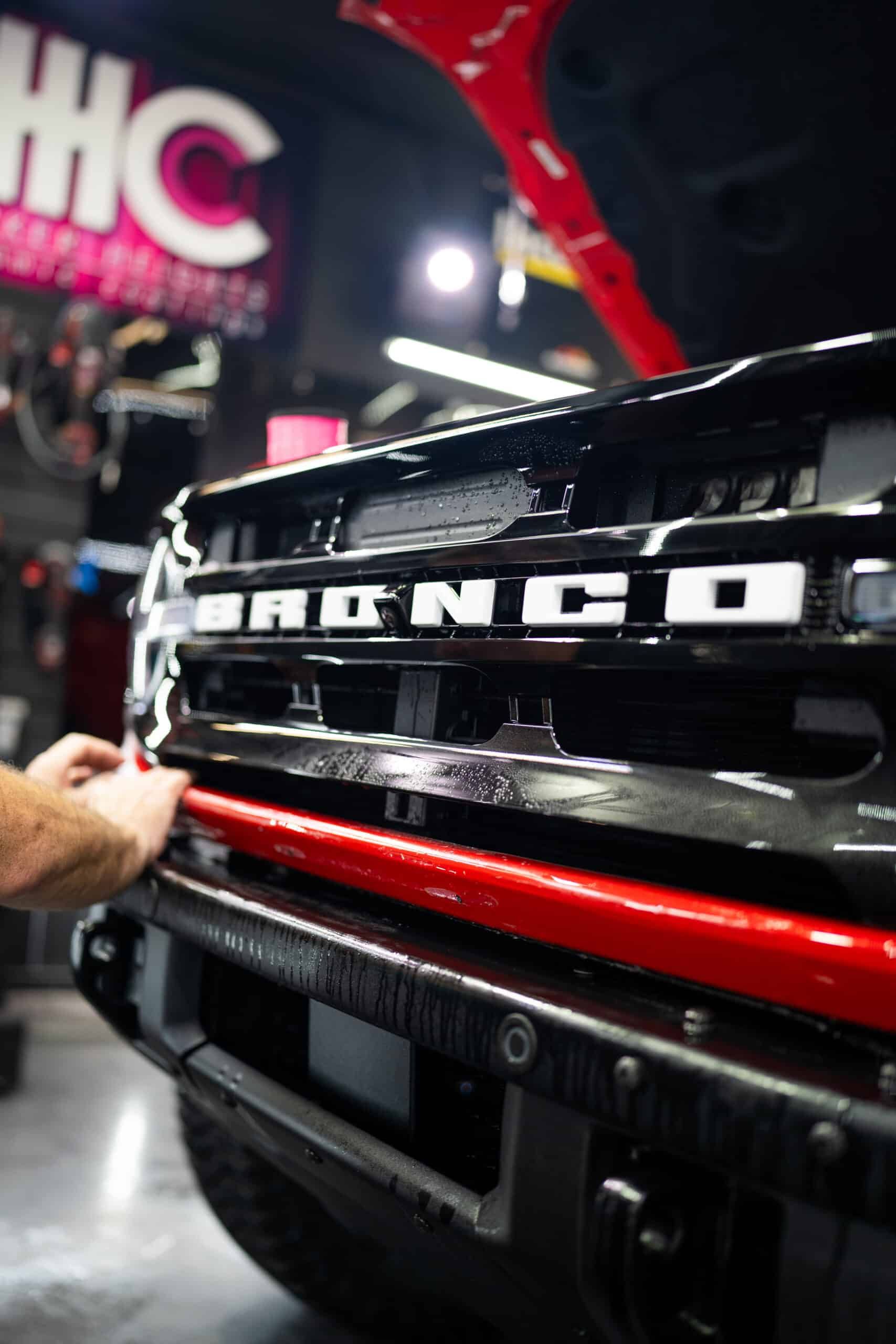 A man is working on the front of a ford bronco