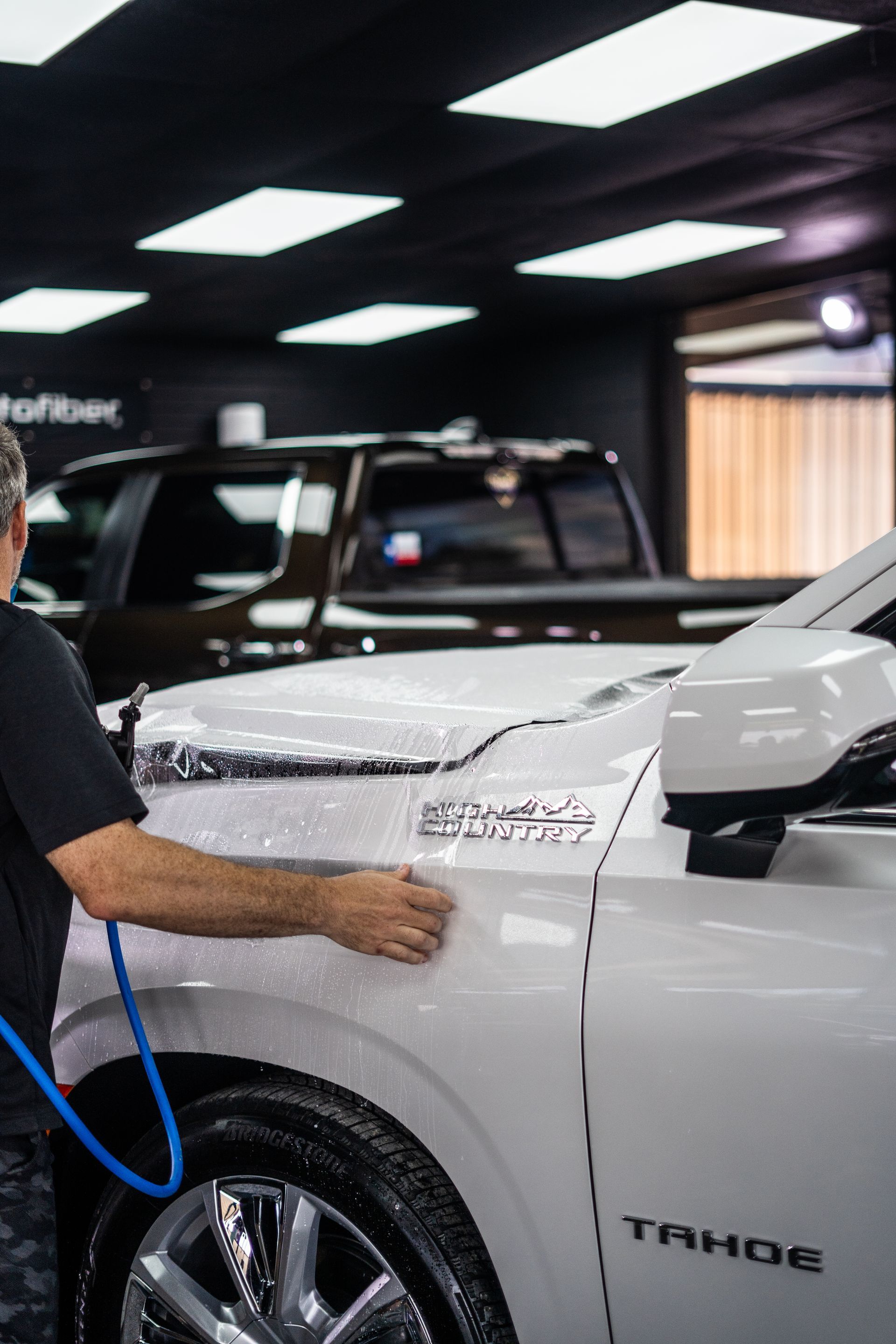 A man is installing a clear bra on a white car.