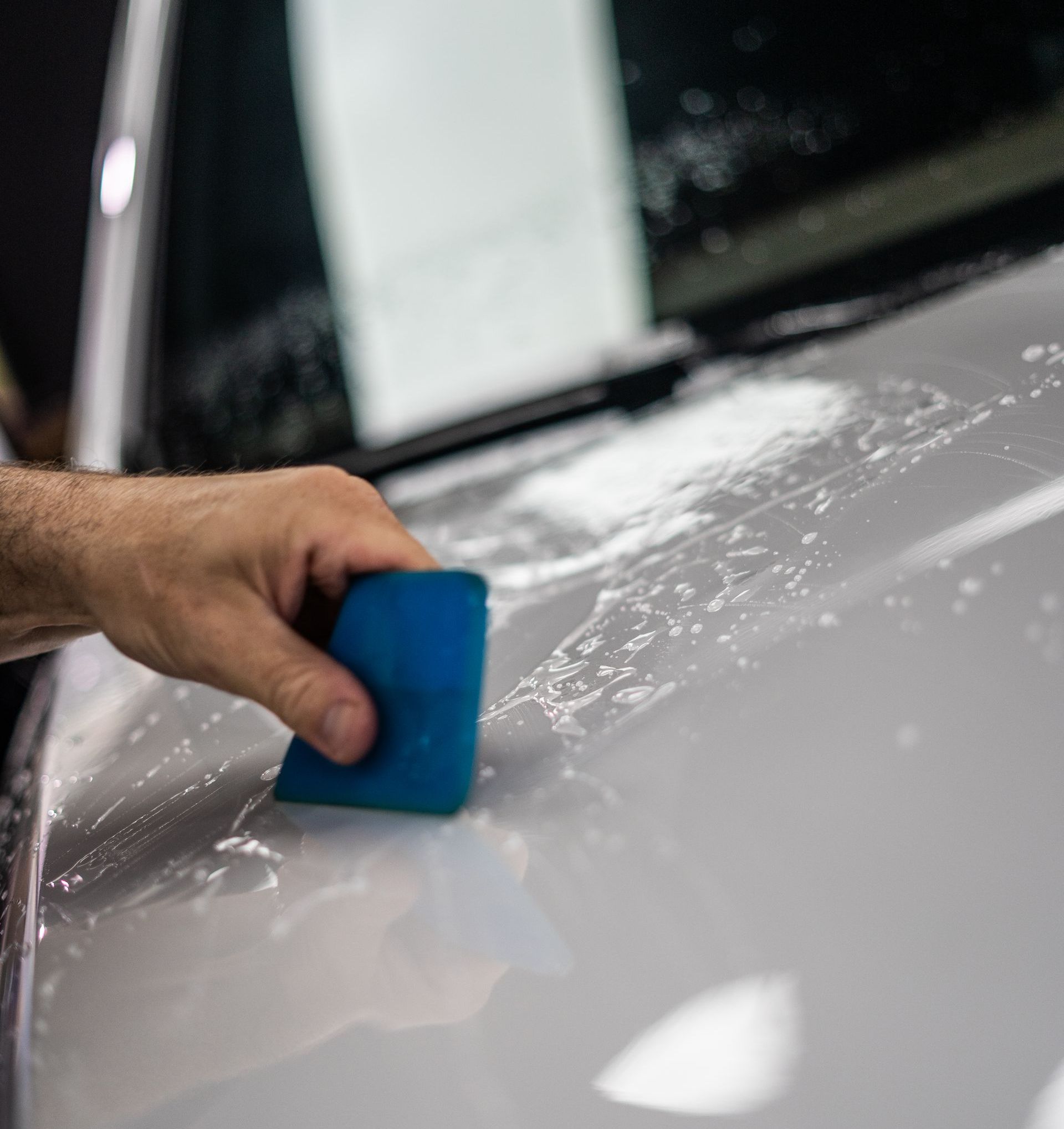 A man is polishing a white car with a machine.