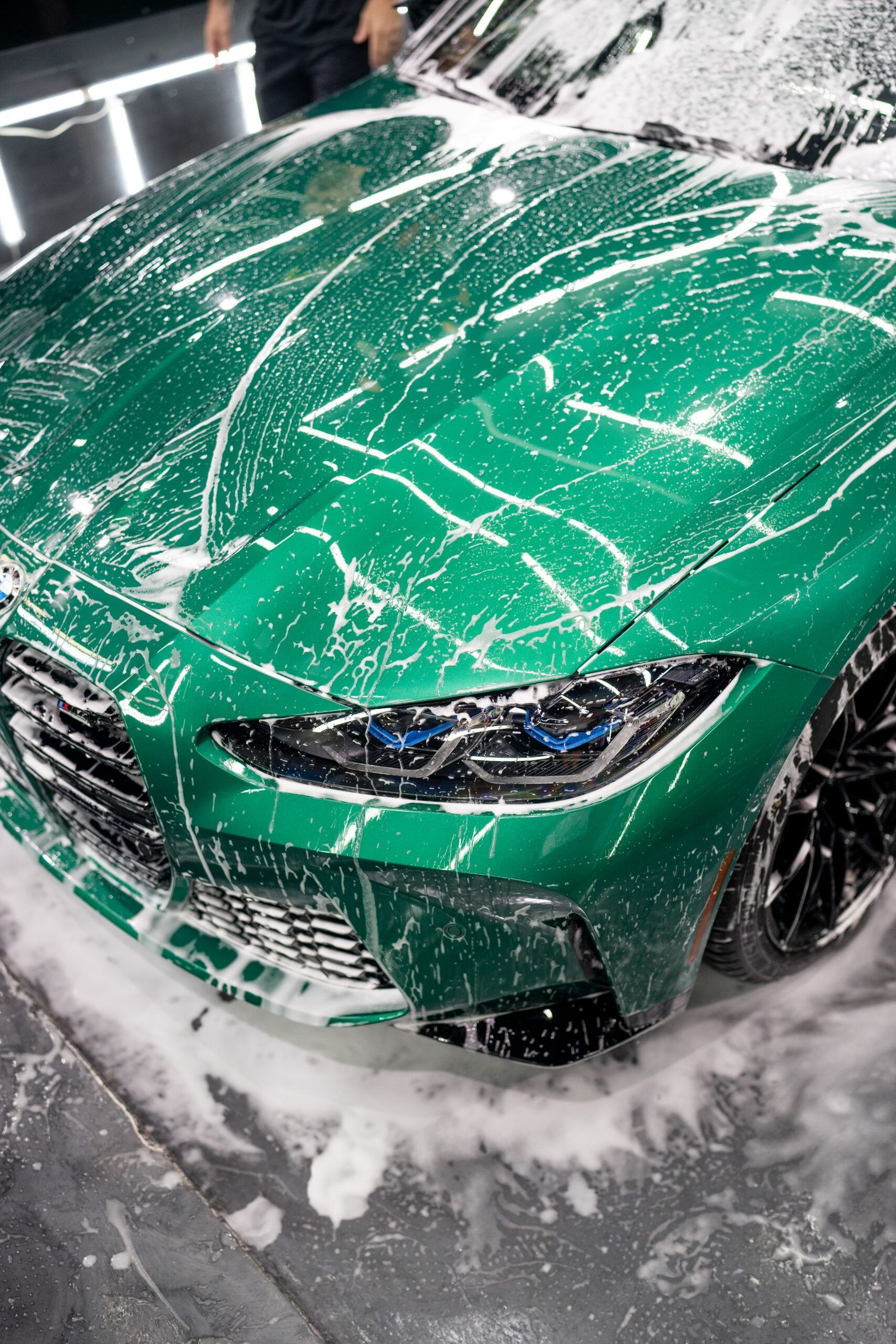 A green car is covered in foam and soap.