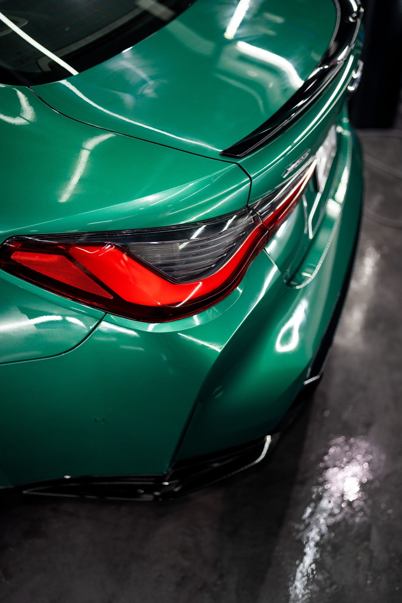 The rear end of a green bmw m4 is shown in a close up.