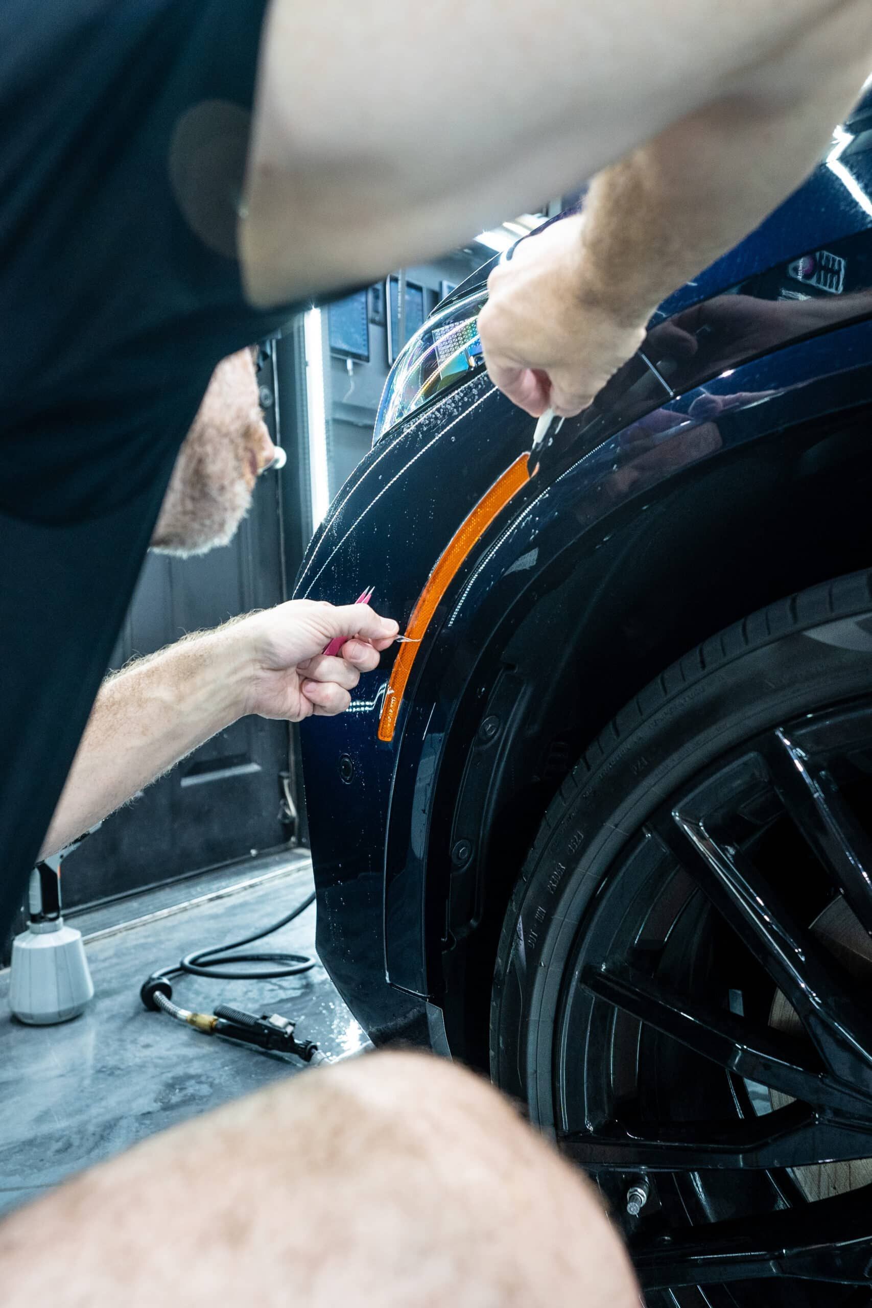 A man is working on the side of a car.