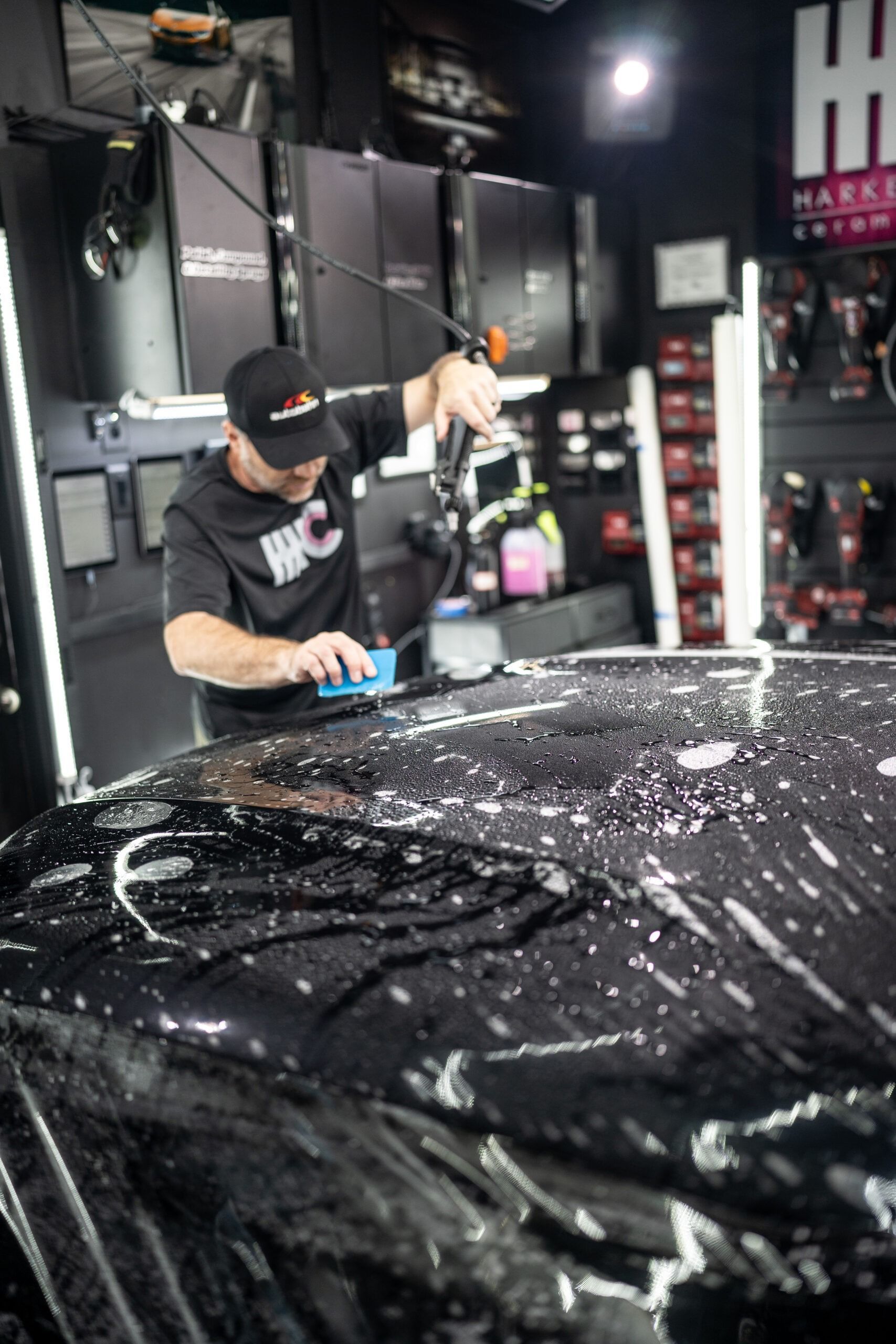 A man is wrapping a car with plastic wrap in a garage.