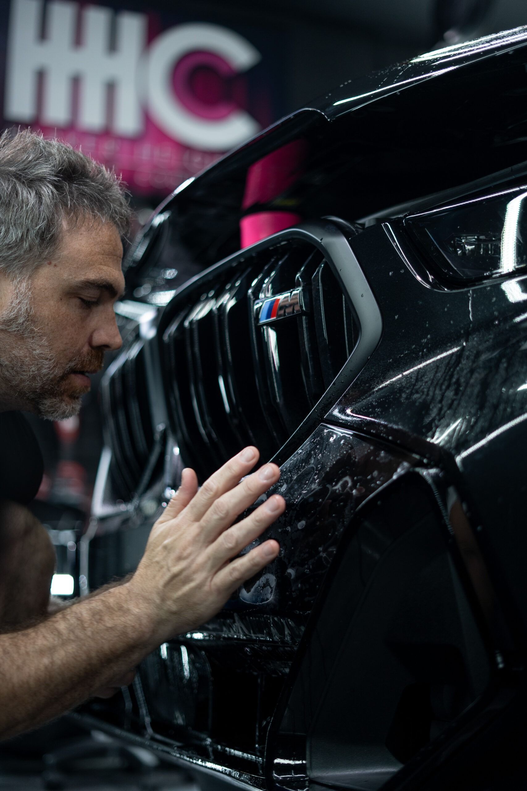 A man is touching the grille of a black car.