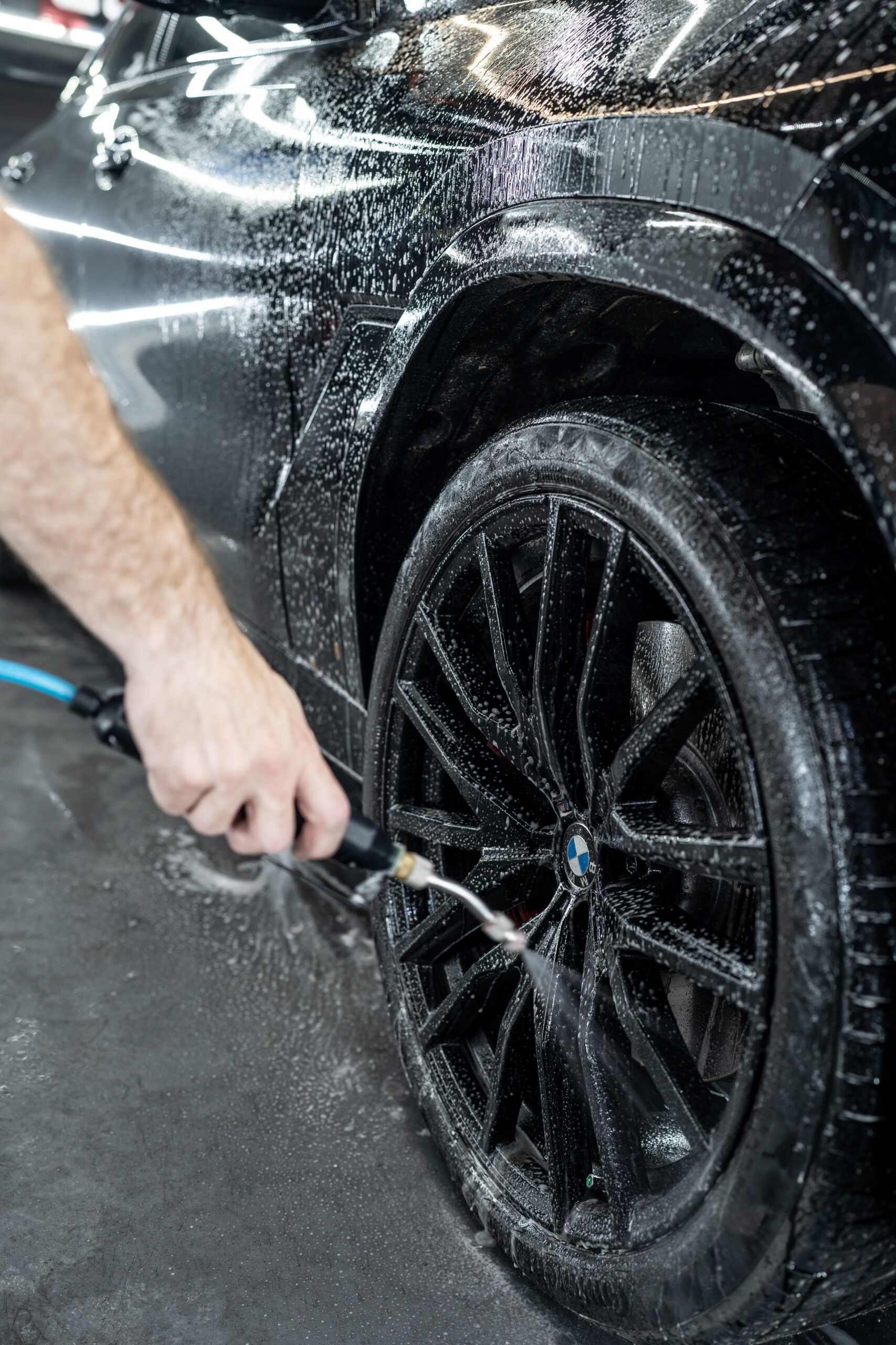A person is washing a car wheel with a brush.