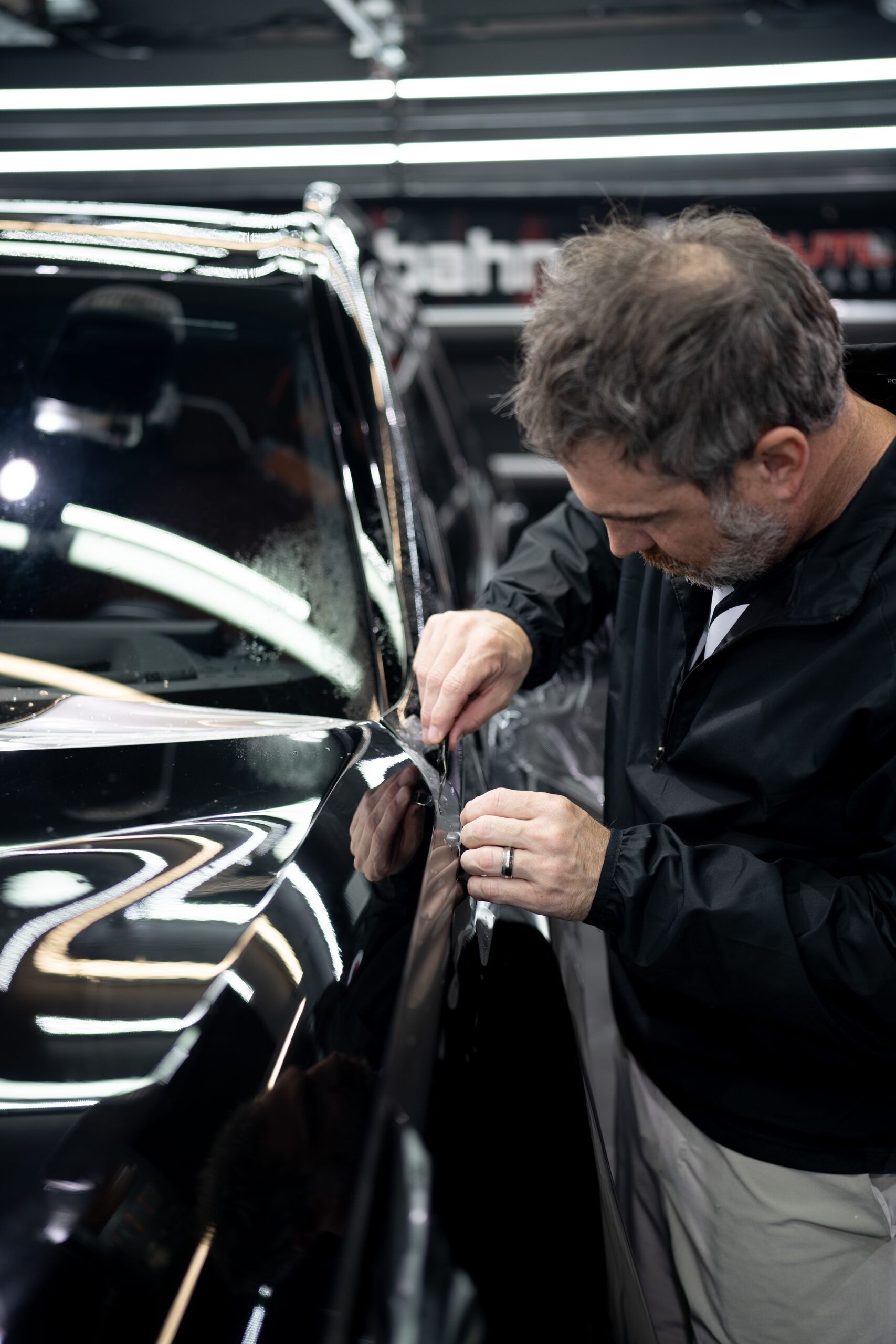 A man is working on a black car in a garage.