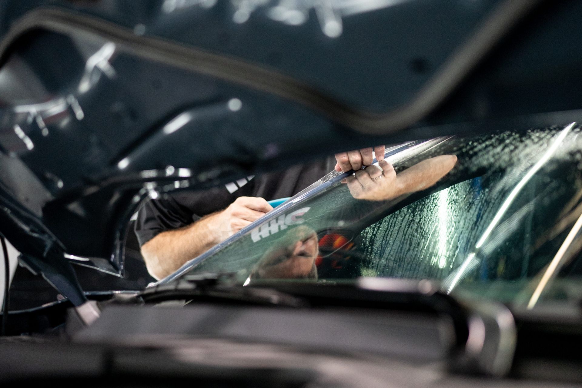 A man is cleaning the windshield of a car.