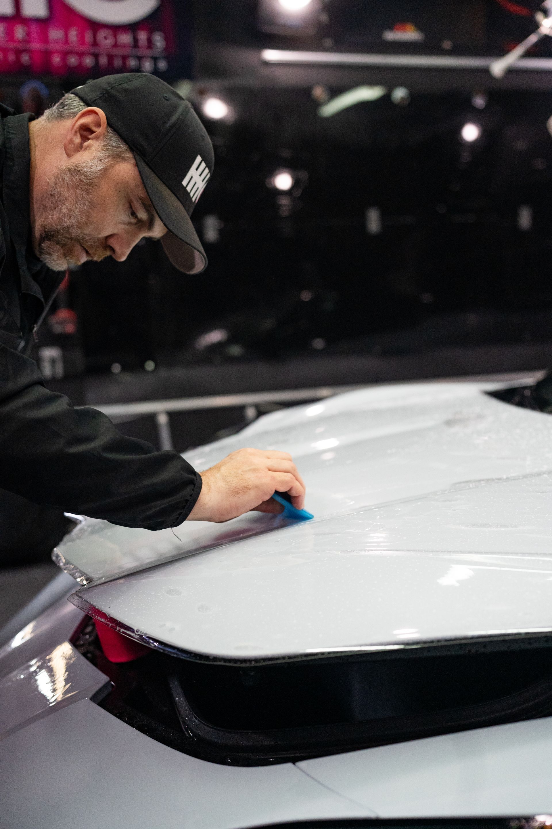 A man is installing a paint protection film of a white car.