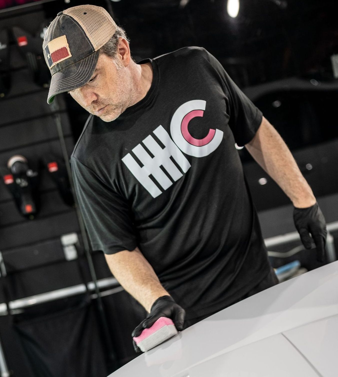 A man wearing a hhc shirt is cleaning a car