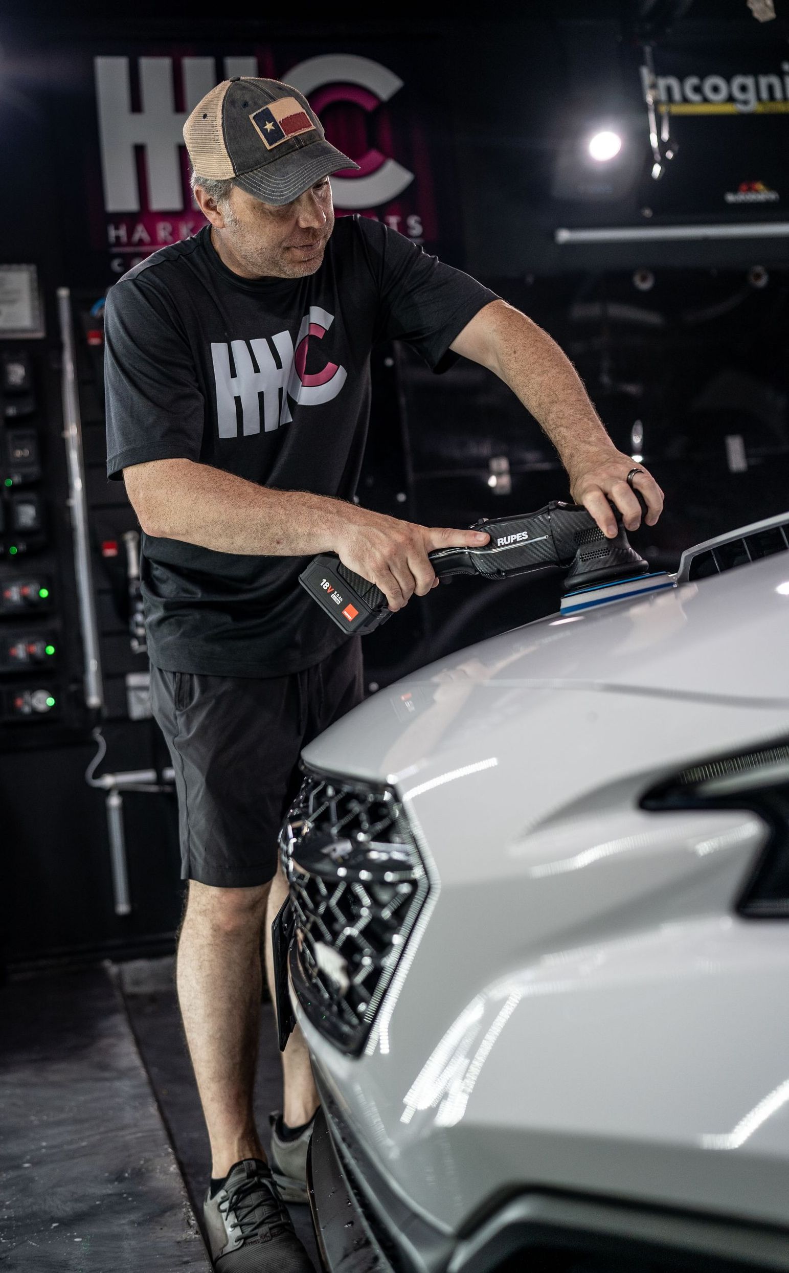 A man is polishing a white car in a garage.