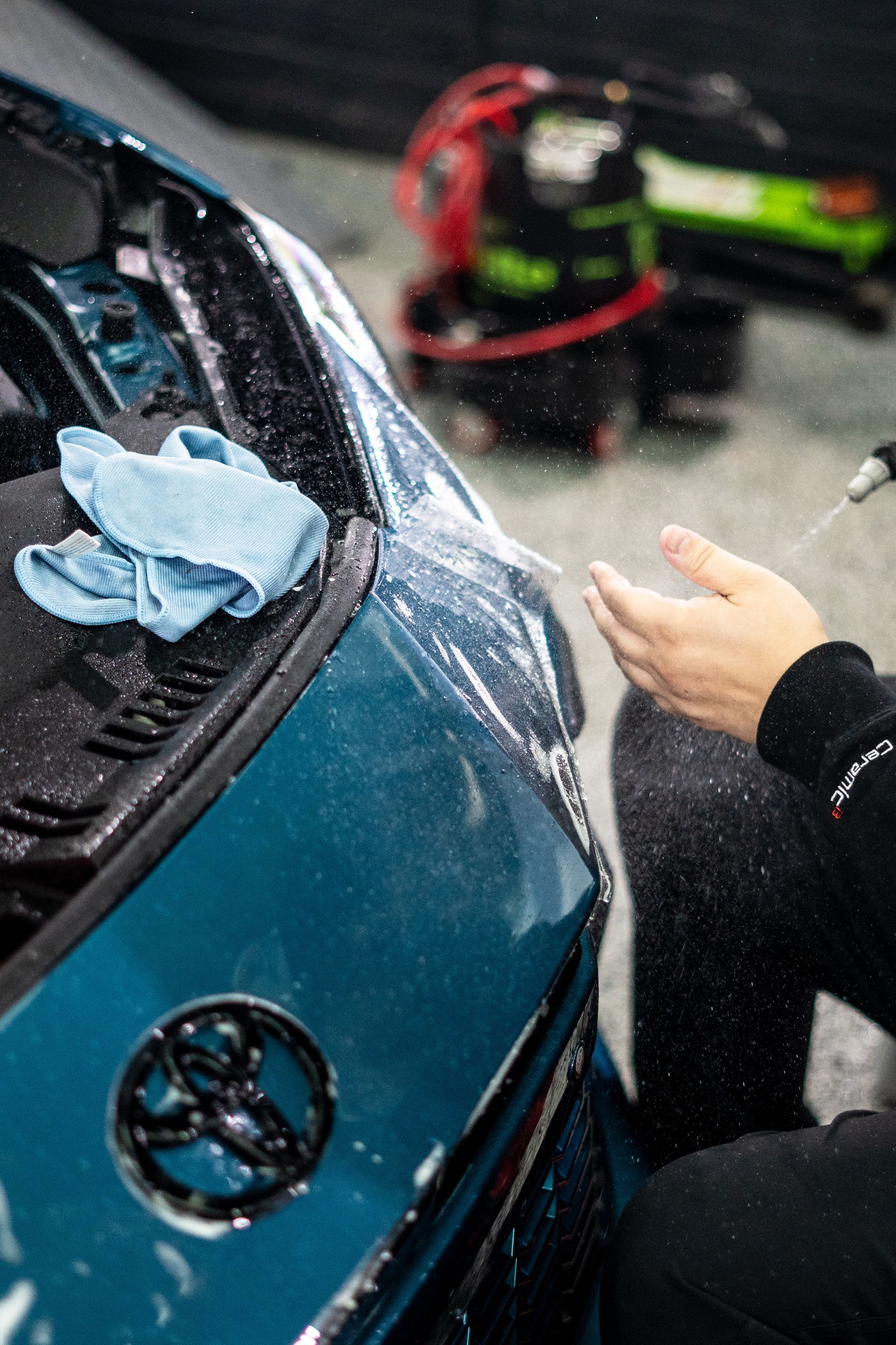 A person is applying a protective film to a blue car.