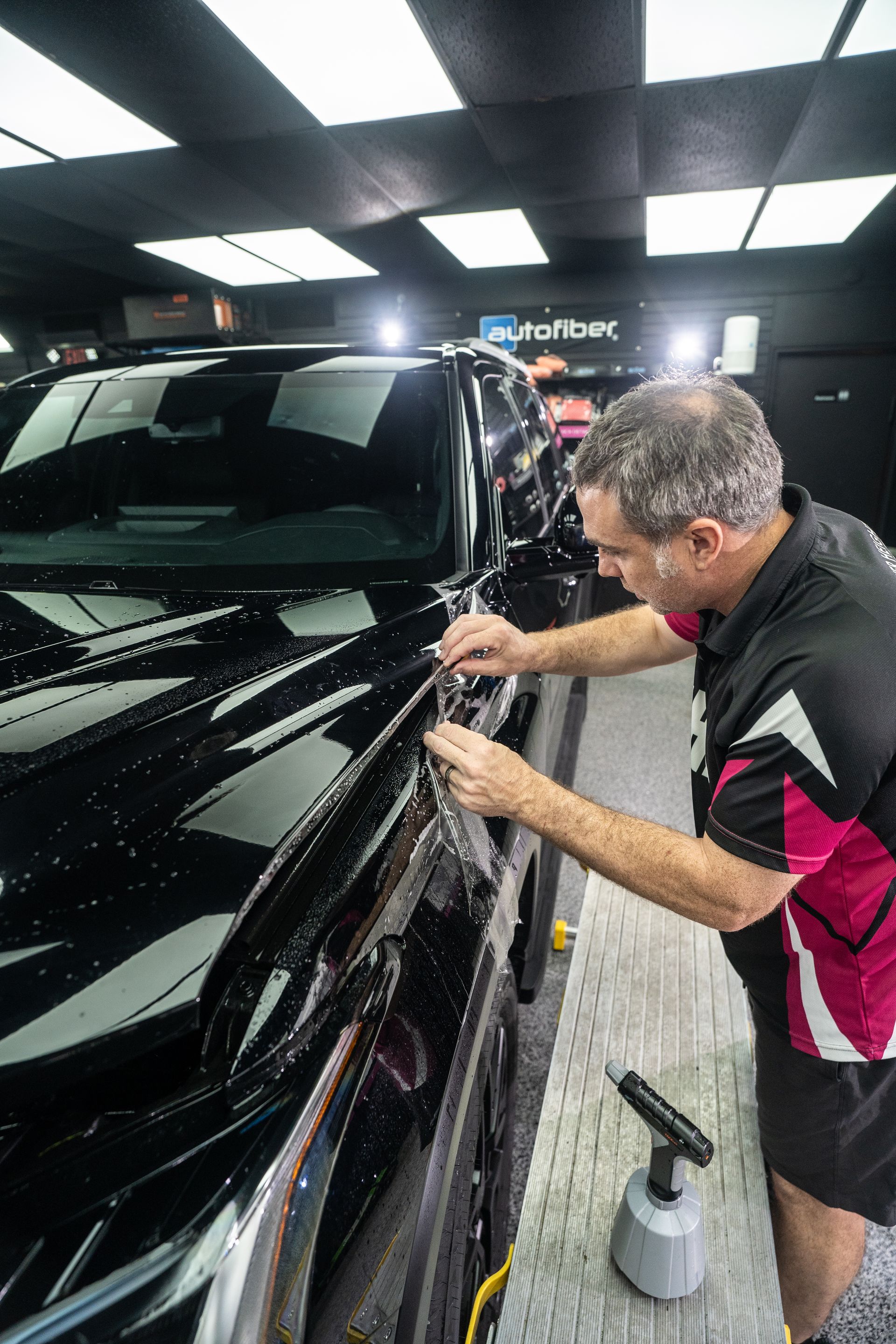 A man is working on a black car in a garage.