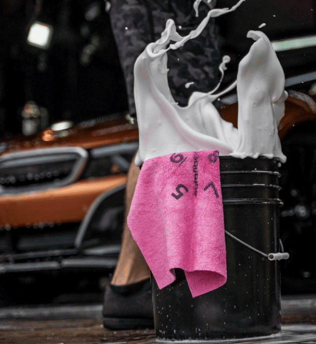 A pink towel with the number 5 on it is in a black bucket