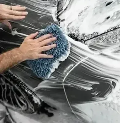 A man is washing a car with a sponge and foam.