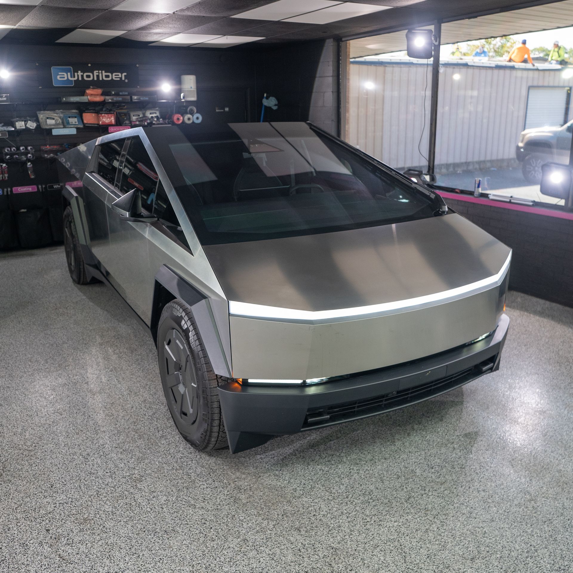 A silver tesla cybertruck is parked in a garage