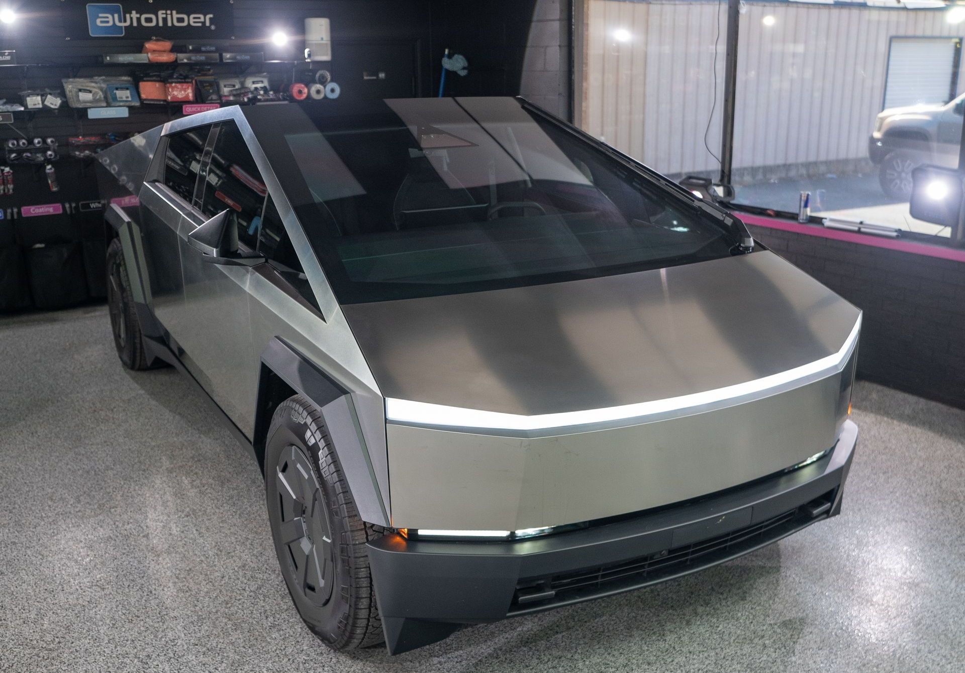 A silver tesla cybertruck is parked in a garage