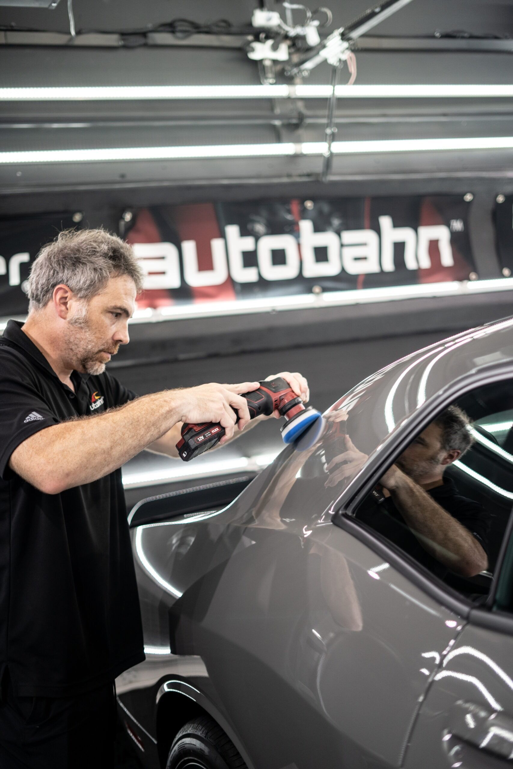 A man is polishing a car in a garage.
