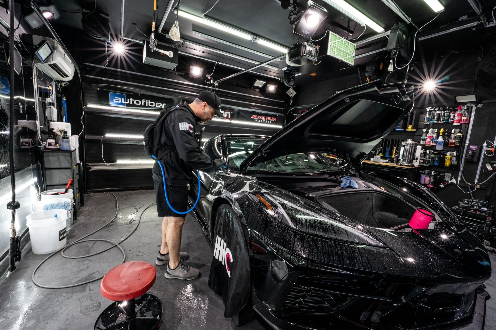 A man is cleaning a red car with a hwc logo on the side