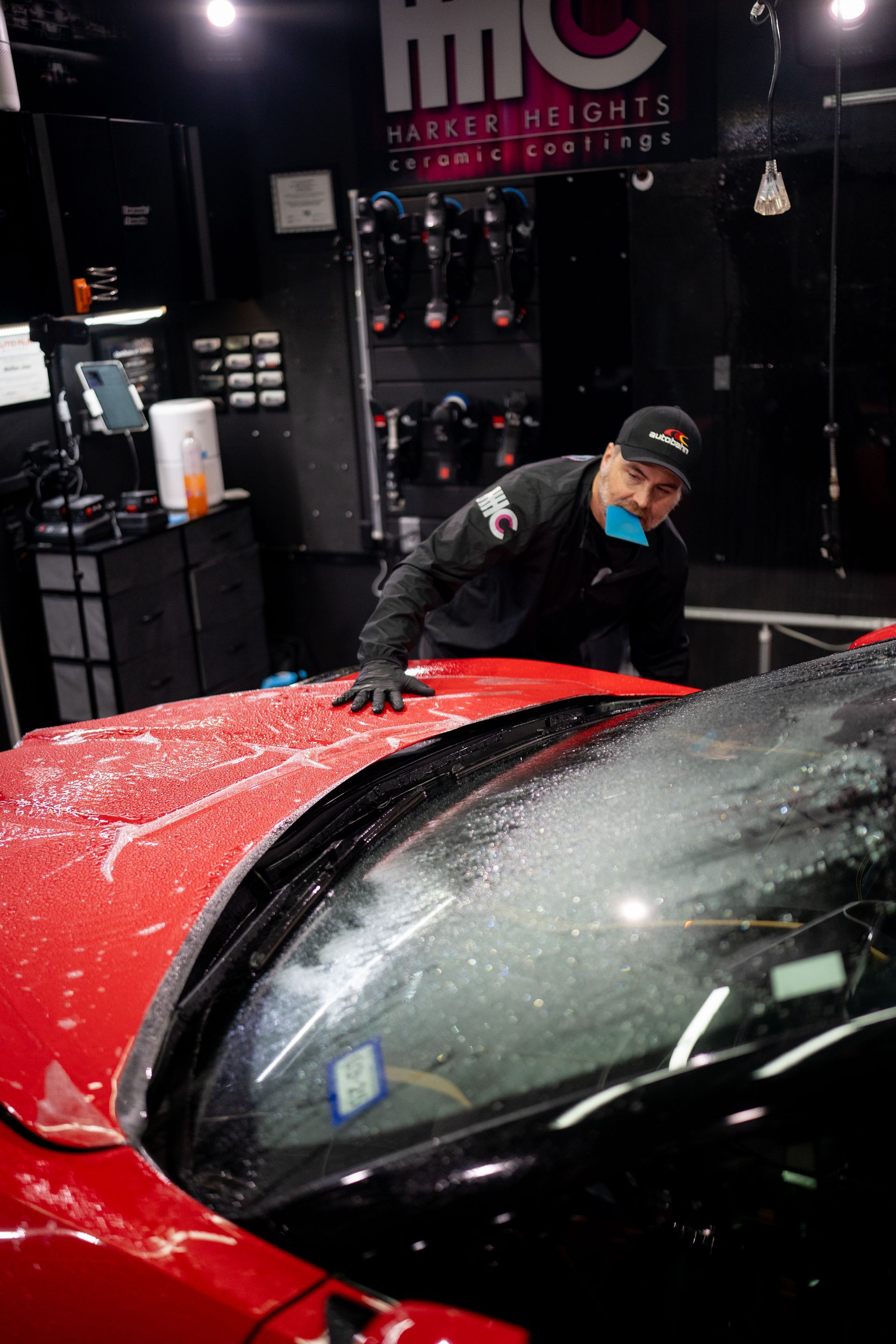 A man is standing next to a red car in a garage.