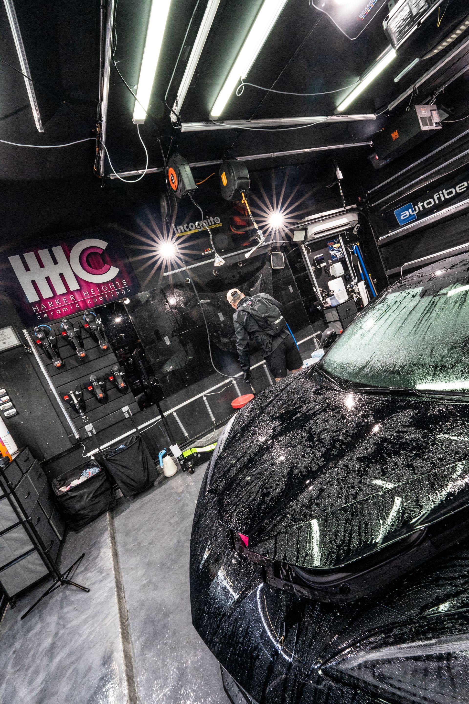 A black car is being cleaned in a garage.