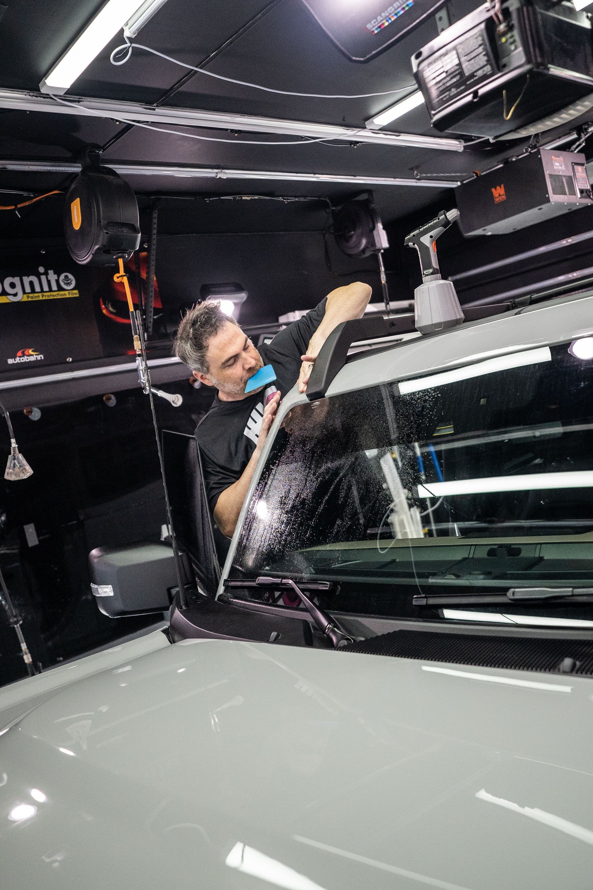 A man wearing a watch is cleaning a car