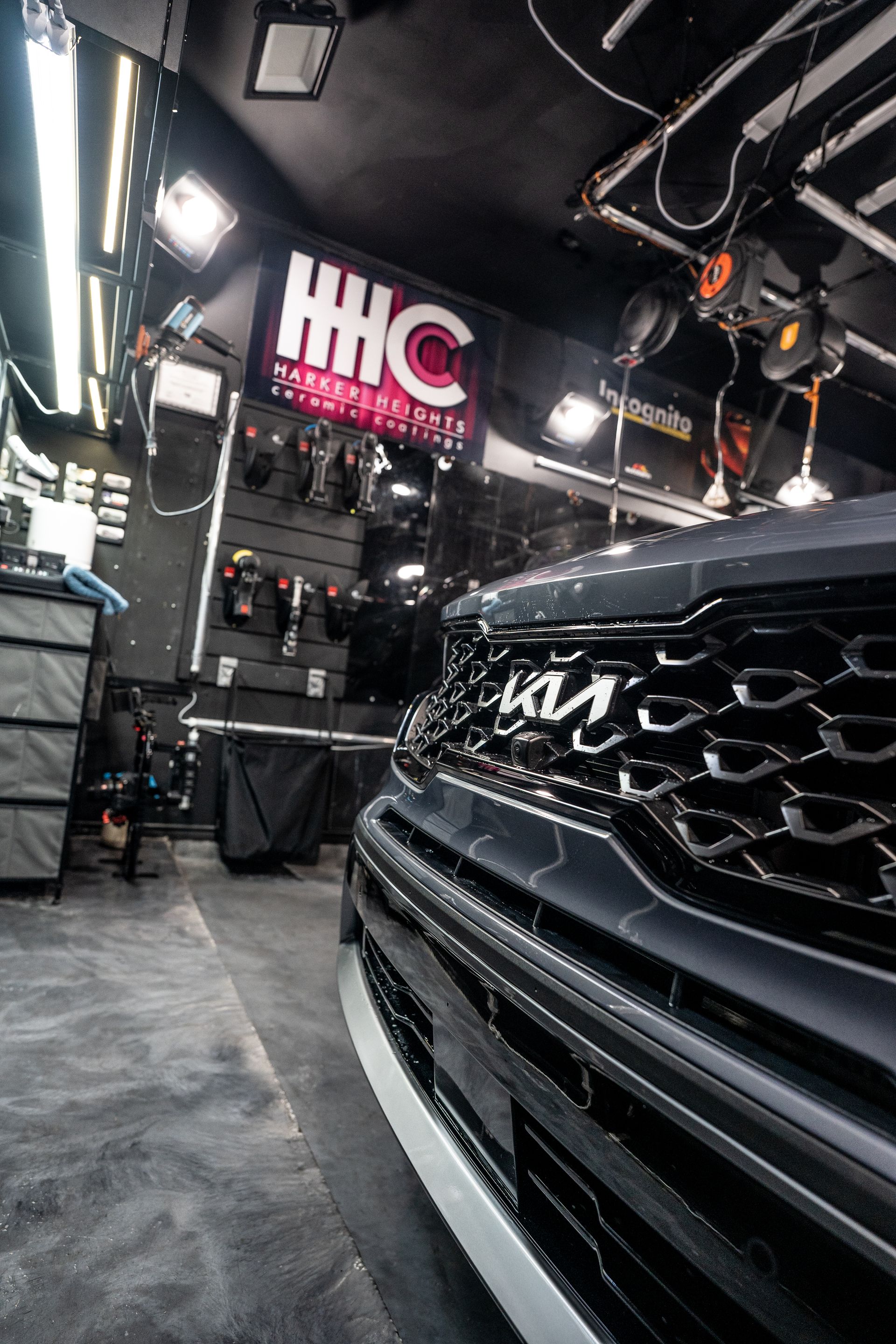 A black car is parked in a garage with a sign above it.