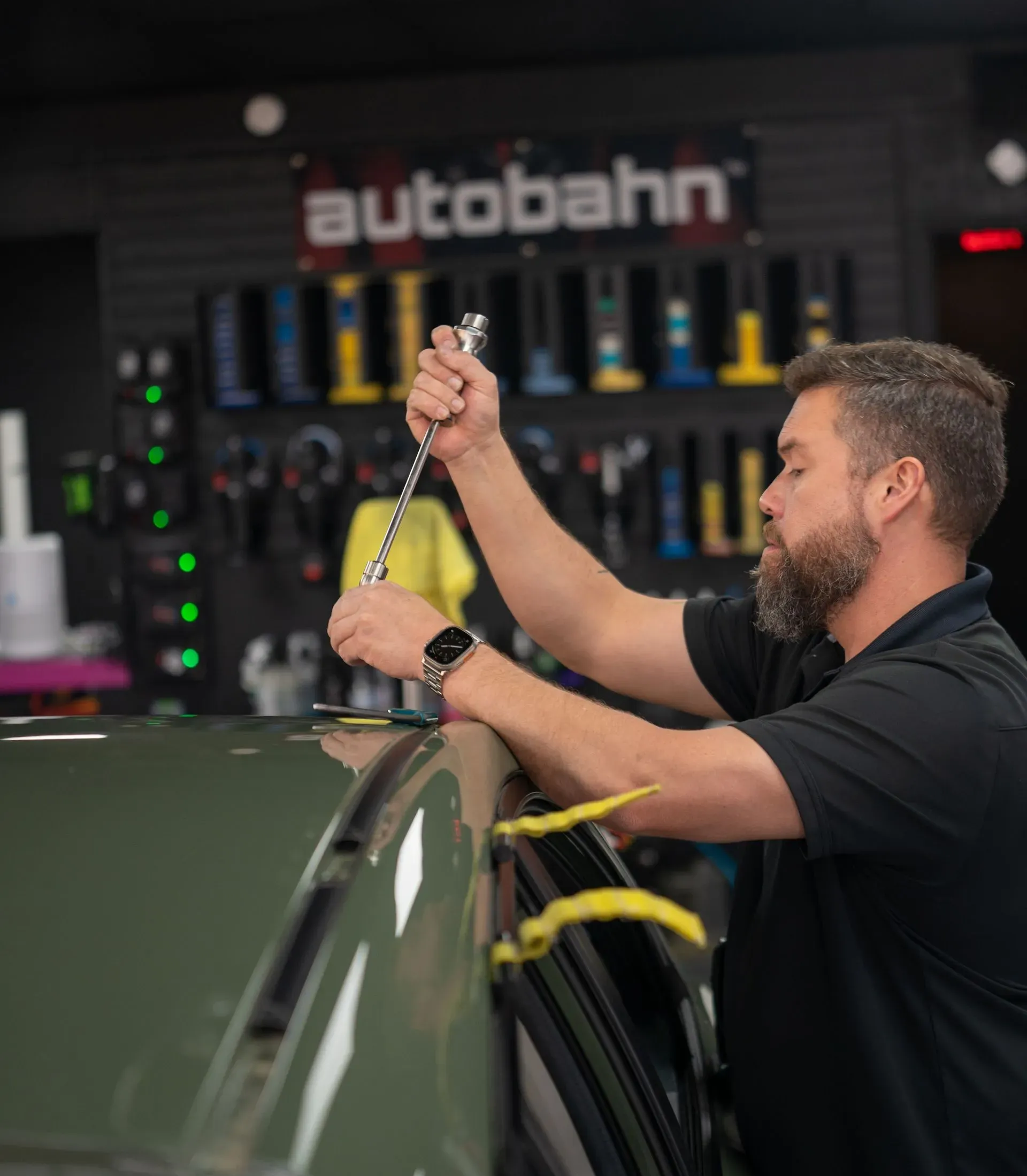 A man is cleaning a red sports car in a garage.