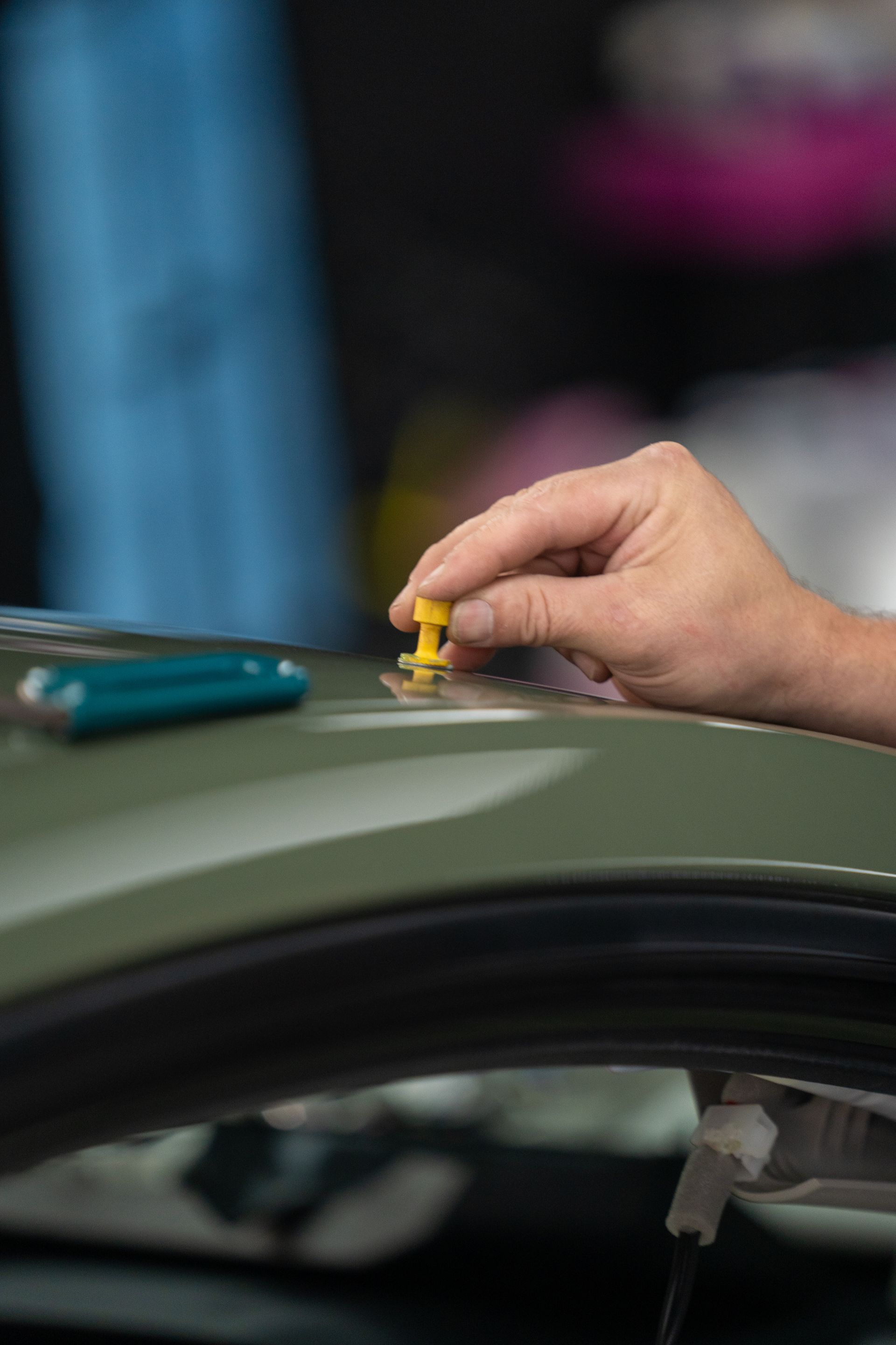 A man is polishing the hood of a red car.