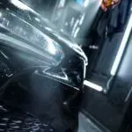 A close up of a person cleaning a car with a hose.