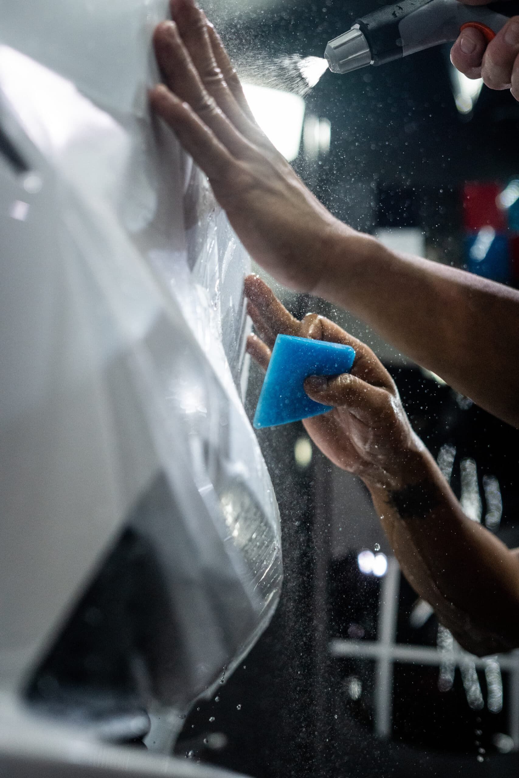 A person is cleaning a car with a blue sponge.