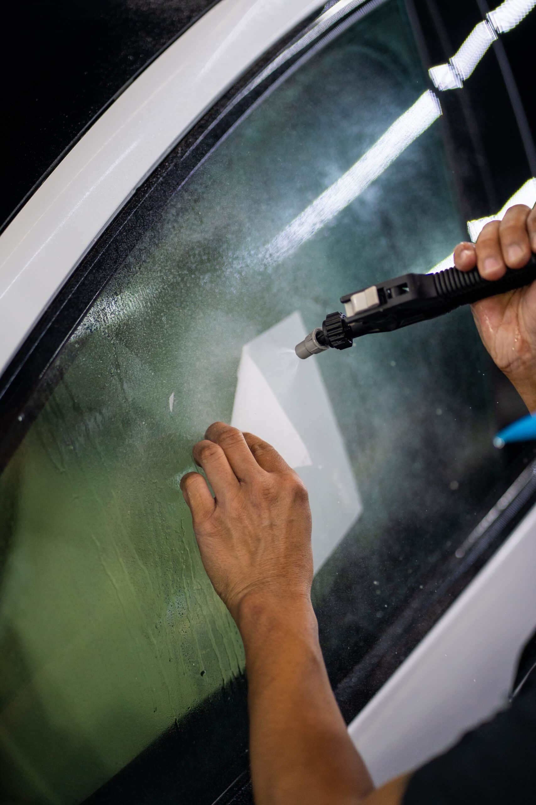 A person is applying window tinting to a car window.