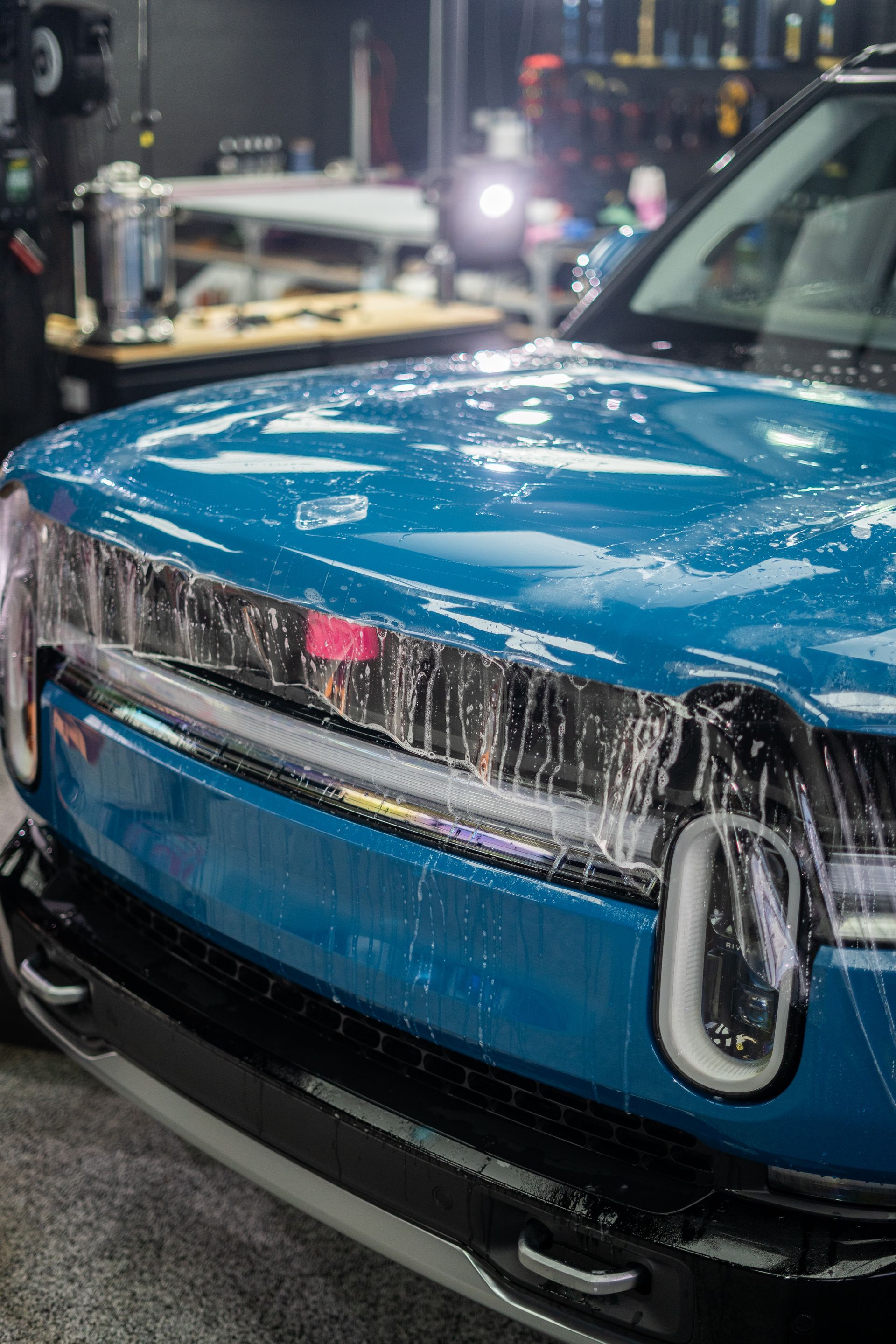 A blue car is sitting in a garage covered in PPF.