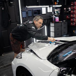 A man is working on a white car in a garage.