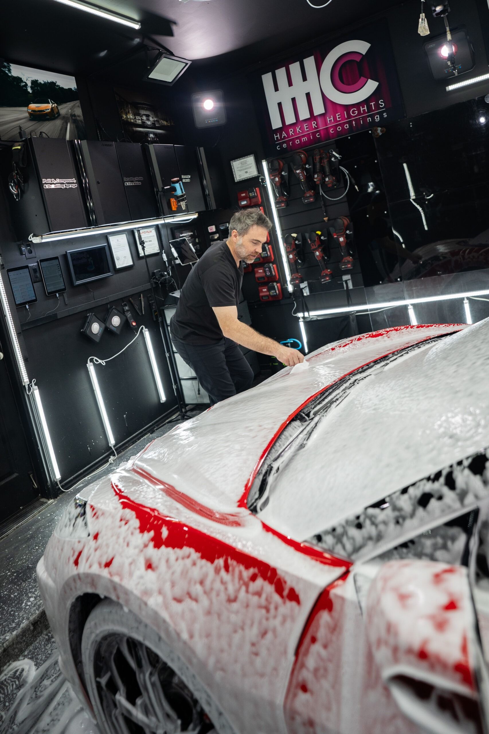 A man is washing a car in a garage.