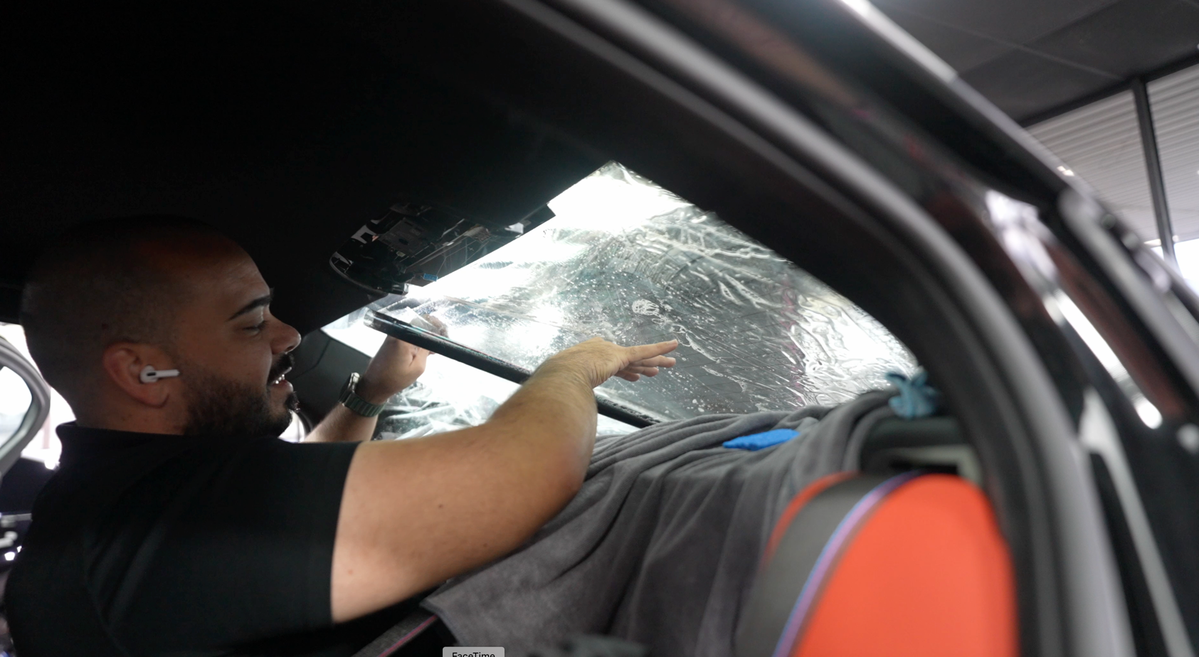 A person is cleaning a car window with a squeegee.